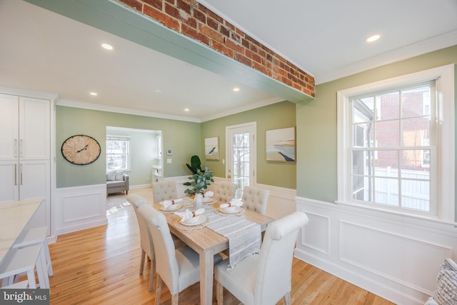 dining room featuring light wood finished floors, wainscoting, and ornamental molding