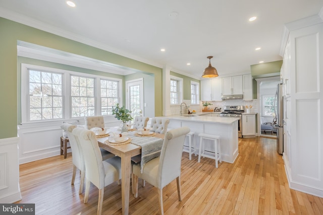 dining room with recessed lighting, a wainscoted wall, light wood-style flooring, and ornamental molding