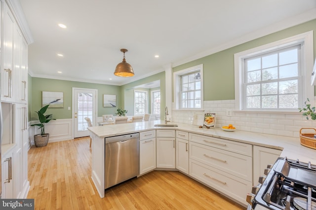 kitchen featuring ornamental molding, white cabinetry, appliances with stainless steel finishes, a peninsula, and wainscoting