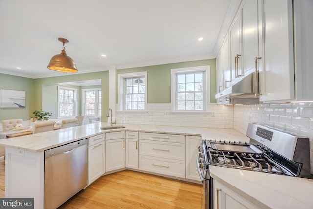 kitchen with crown molding, light stone counters, stainless steel appliances, white cabinetry, and a sink