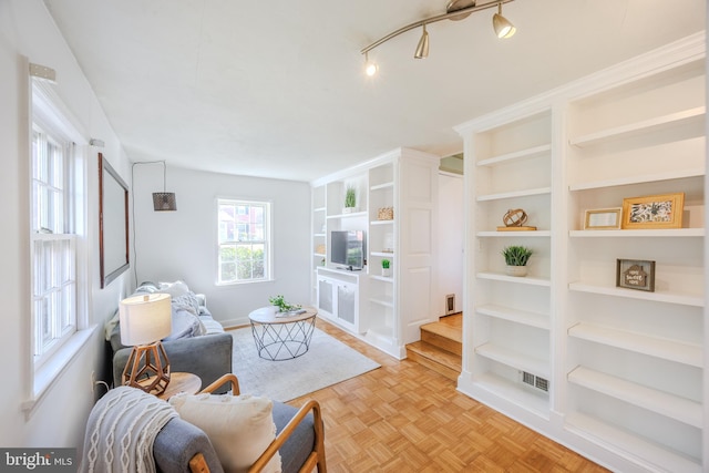 living area with built in features and track lighting