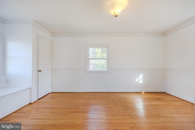 unfurnished room featuring a wainscoted wall and light wood-style floors