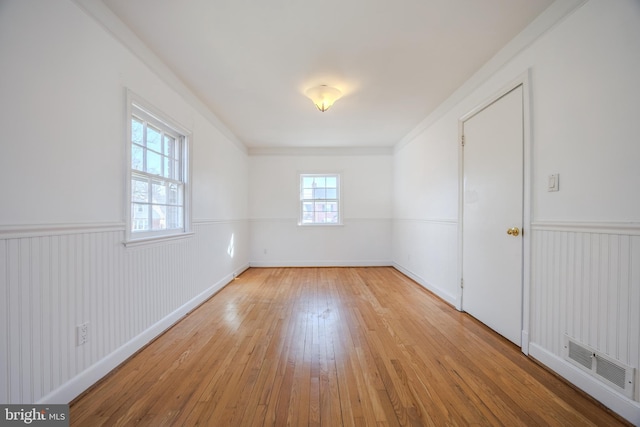 unfurnished room with visible vents, wainscoting, and light wood finished floors