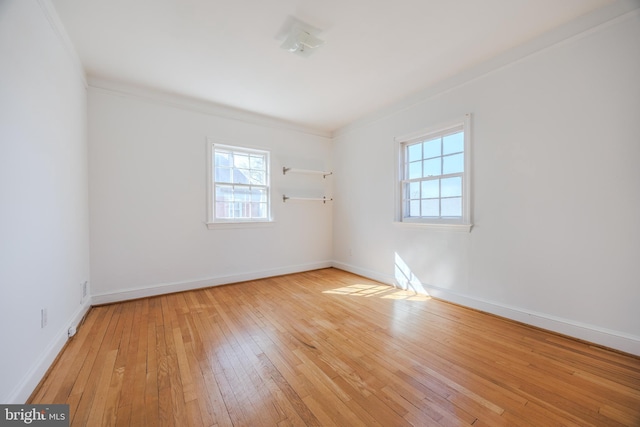 spare room featuring baseboards, light wood finished floors, and ornamental molding