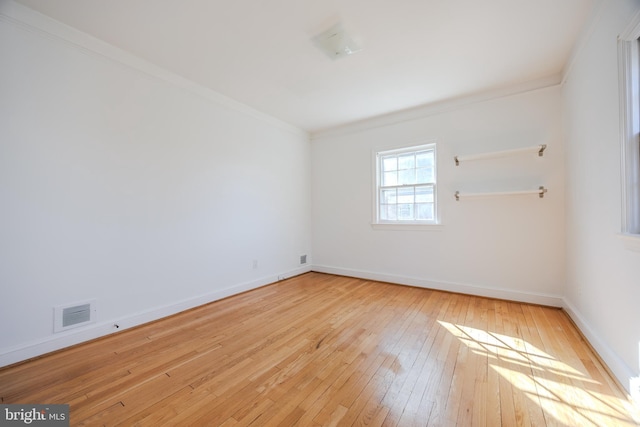 empty room with visible vents, wood-type flooring, baseboards, and ornamental molding