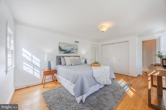 bedroom featuring multiple windows, visible vents, light wood-type flooring, and a closet