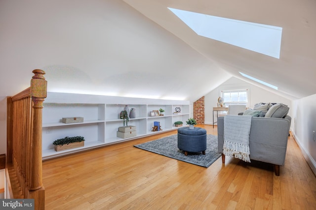 interior space featuring built in shelves, vaulted ceiling with skylight, and wood finished floors