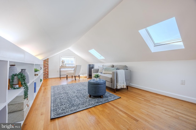 sitting room with lofted ceiling with skylight, baseboards, and wood finished floors