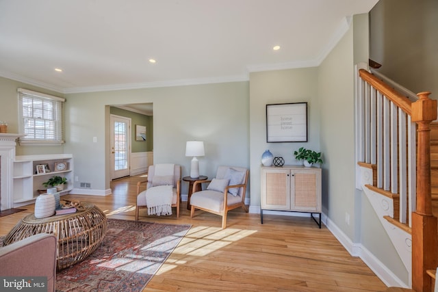 sitting room with light wood finished floors, crown molding, and stairs