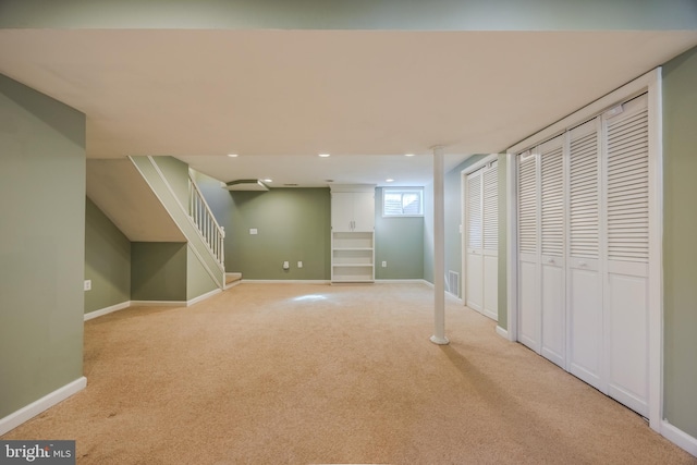 below grade area with visible vents, baseboards, light colored carpet, stairs, and recessed lighting