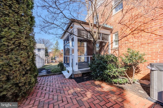 exterior space with brick siding, central air condition unit, and a sunroom