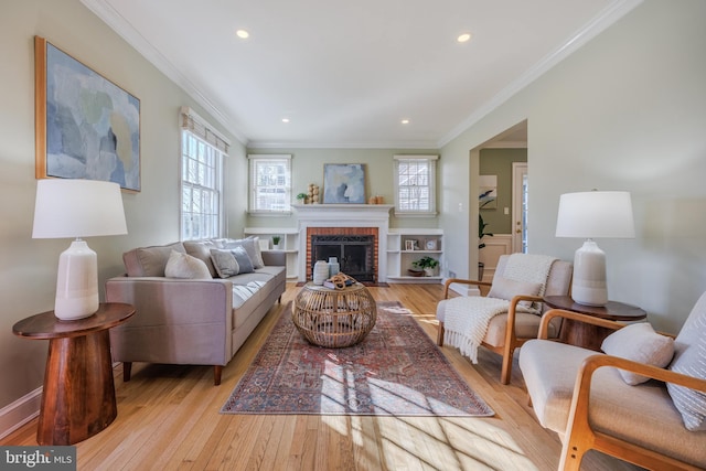 living room with recessed lighting, light wood-style flooring, a brick fireplace, and crown molding