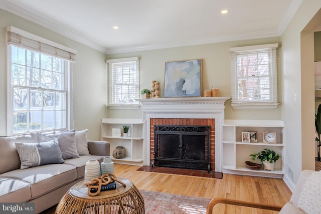 living room with recessed lighting, ornamental molding, a brick fireplace, and wood finished floors