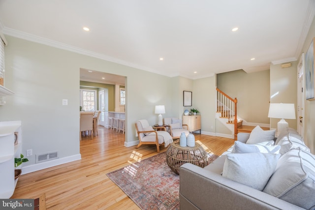 living room featuring visible vents, ornamental molding, and light wood finished floors