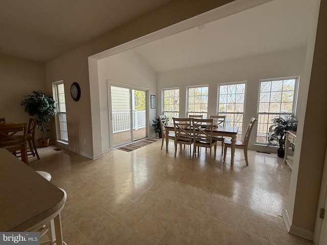 dining room with high vaulted ceiling and baseboards