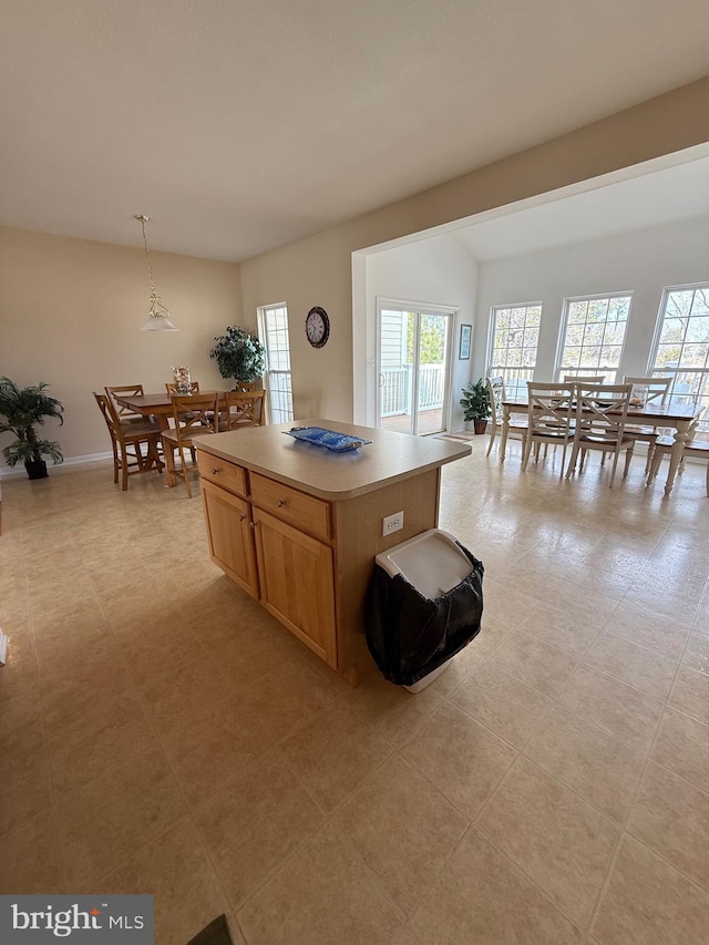 kitchen featuring hanging light fixtures, a kitchen island, baseboards, and light countertops