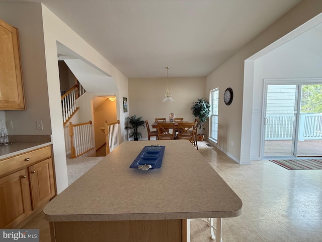 kitchen with a kitchen island, baseboards, light countertops, and decorative light fixtures