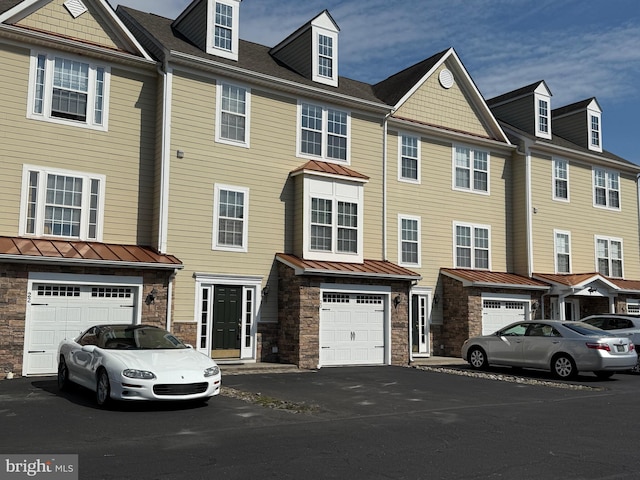 multi unit property featuring stone siding, a standing seam roof, metal roof, and an attached garage