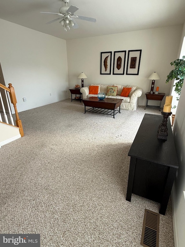 living room featuring stairs, visible vents, a ceiling fan, and carpet flooring