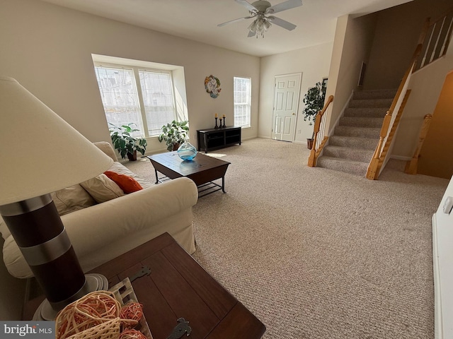 living area featuring carpet floors, ceiling fan, baseboards, and stairs