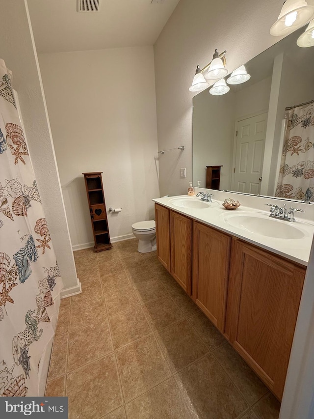 bathroom with double vanity, toilet, a sink, and tile patterned floors