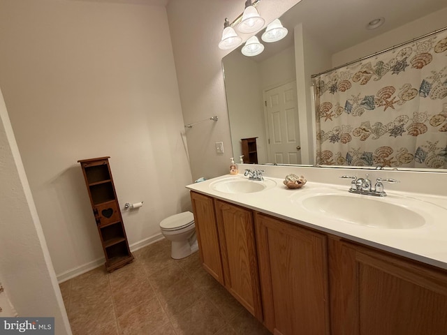 bathroom with baseboards, a sink, toilet, and double vanity