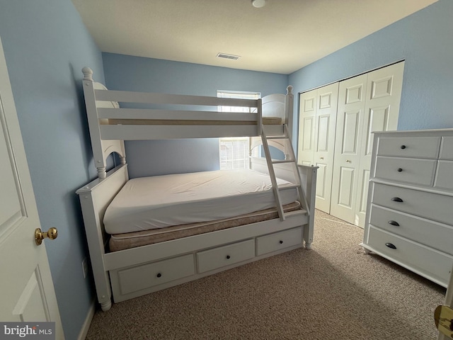 carpeted bedroom with a closet and visible vents