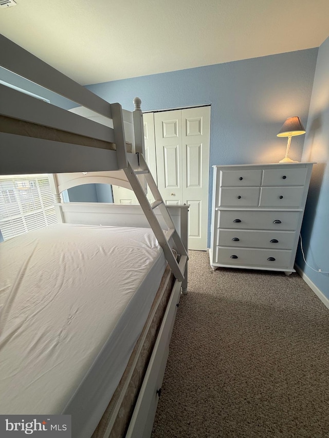 unfurnished bedroom with a closet, dark carpet, and baseboards