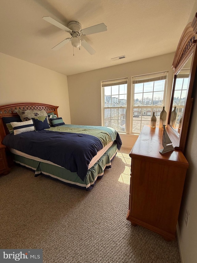 bedroom with carpet, ceiling fan, multiple windows, and visible vents