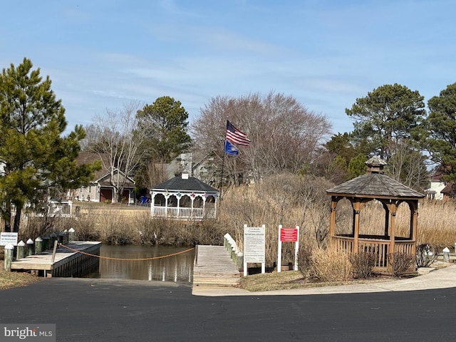 view of community with a gazebo, a dock, and a water view