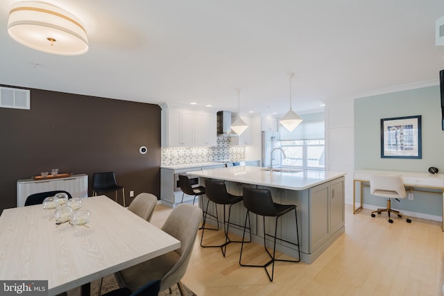 kitchen with visible vents, a sink, high quality fridge, wall chimney exhaust hood, and light countertops