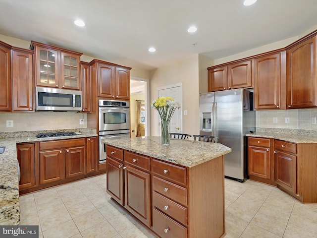 kitchen with light stone countertops, light tile patterned floors, appliances with stainless steel finishes, and recessed lighting