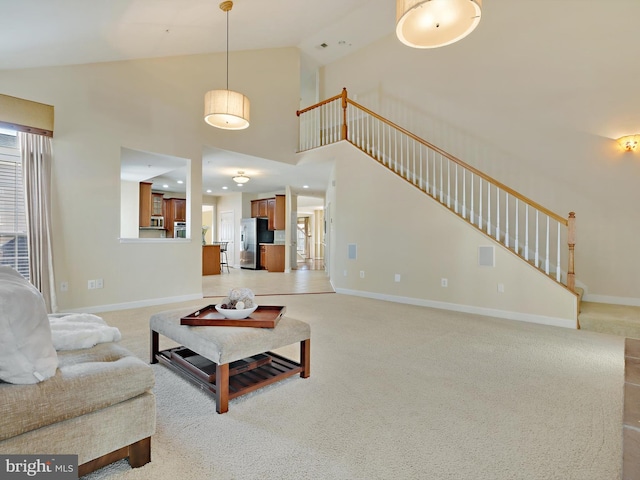 living room with stairs, high vaulted ceiling, baseboards, and light colored carpet