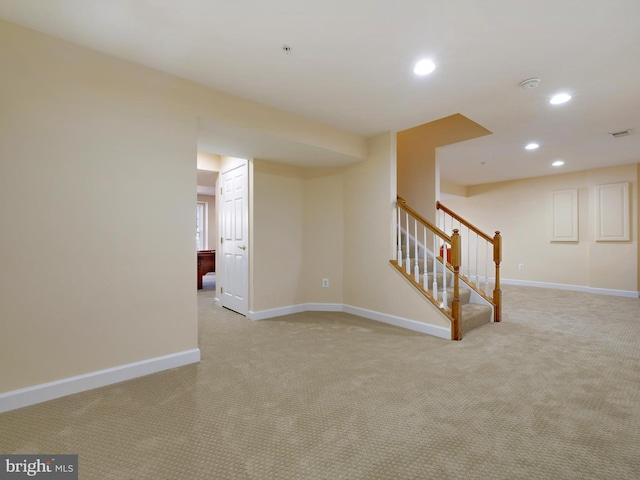 empty room featuring recessed lighting, light colored carpet, stairway, and baseboards