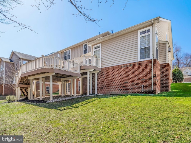 rear view of property with stairway, brick siding, a lawn, and a deck