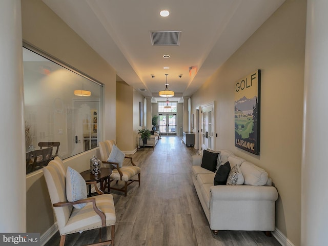 corridor with decorative columns, wood finished floors, visible vents, and baseboards