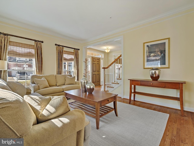 living area featuring crown molding, stairs, baseboards, and wood finished floors