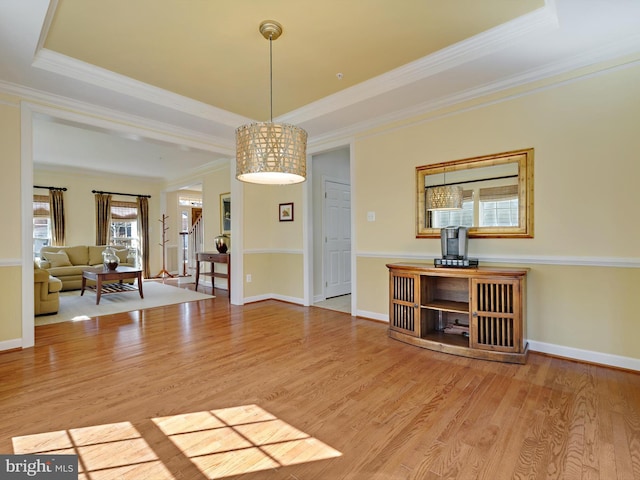 interior space featuring crown molding, a tray ceiling, and wood finished floors