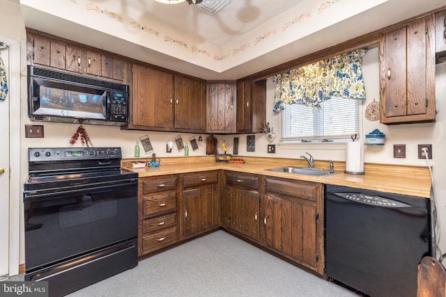 kitchen with black appliances, dark brown cabinets, a raised ceiling, and a sink