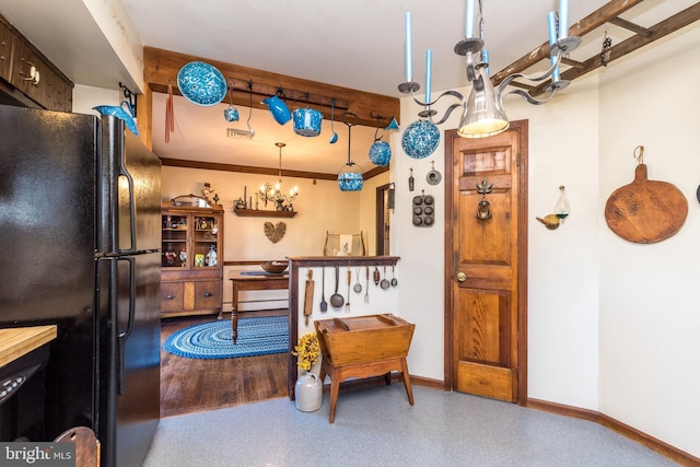 kitchen with an inviting chandelier, crown molding, baseboards, and freestanding refrigerator