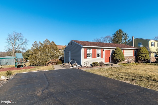 view of front facade with driveway, a front yard, and a playground