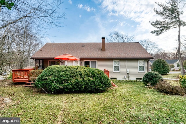 rear view of house featuring a wooden deck, roof with shingles, and a yard