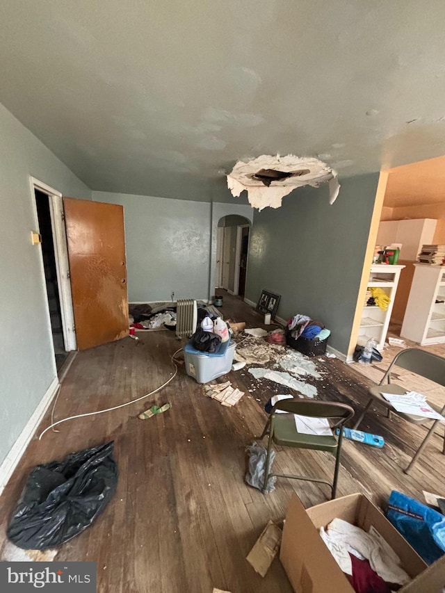 dining room with baseboards, arched walkways, and hardwood / wood-style floors