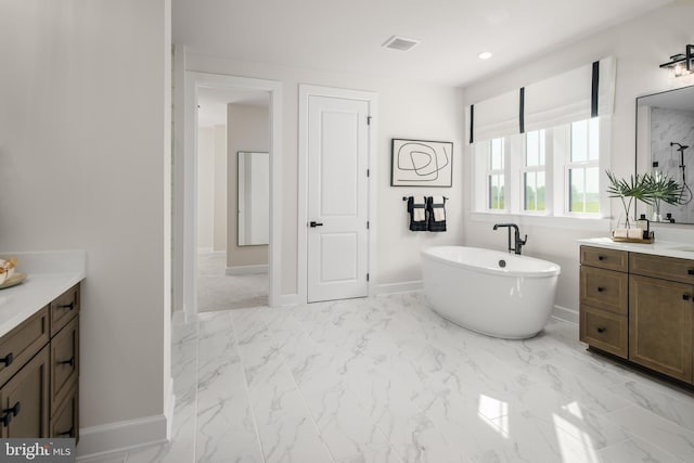 full bathroom with marble finish floor, visible vents, a freestanding bath, vanity, and baseboards