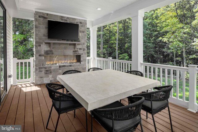 wooden terrace with a fireplace and outdoor dining space