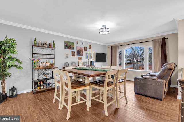 dining room featuring baseboards, wood finished floors, and crown molding