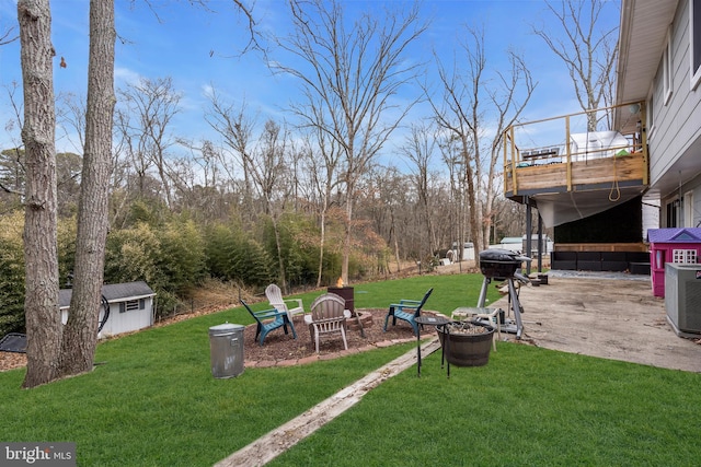 view of yard featuring an outdoor fire pit, central AC unit, a patio, a balcony, and an outbuilding