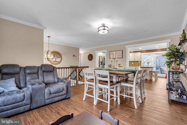 living room featuring a notable chandelier, ornamental molding, and light wood-style floors