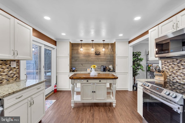 kitchen featuring wooden counters, appliances with stainless steel finishes, white cabinets, and wood finished floors