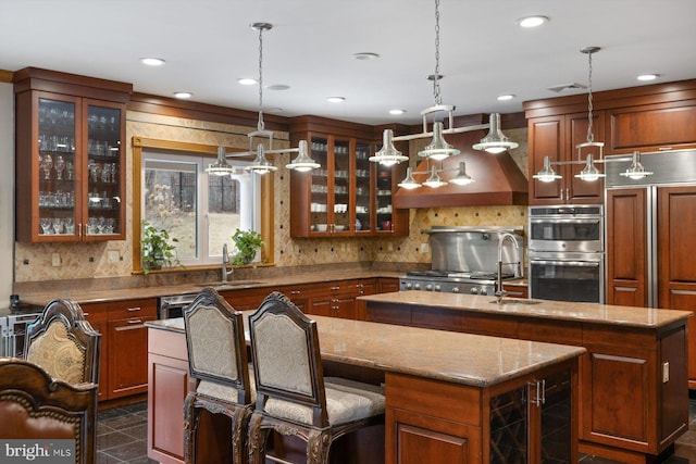 kitchen with a sink, a center island with sink, backsplash, and stainless steel double oven